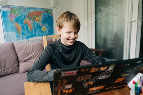 Preview: A teenage boy uses a laptop for online communication while sitting in a room at home.