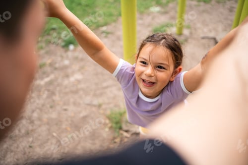 Preview: Young child daughter playing with father on the workout outdoors gym. Happy emotions. Healthy family