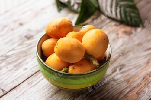Preview: Ripe medlar fruit (Eriobotrya japonica) and green medlar leaves on wooden table