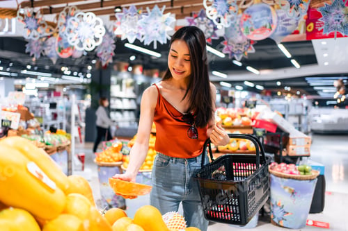 Preview: Asian young beautiful woman holding grocery basket walk in supermarket.