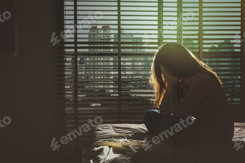 Preview: depressed Women sitting head in hands on the bed in the dark bedroom