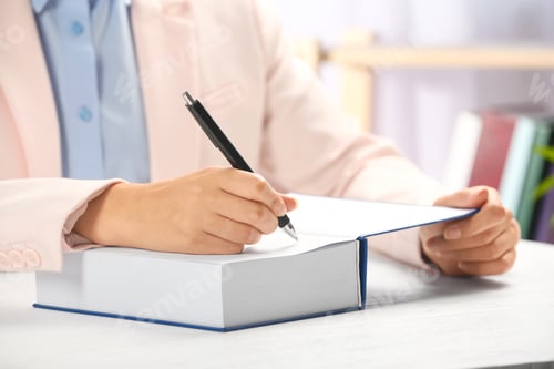 Preview: Writer signing autograph in book at table, closeup