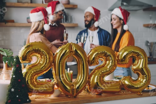 Visualização: Grupo de jovens jantando com decoração de Ano Novo em primeiro plano