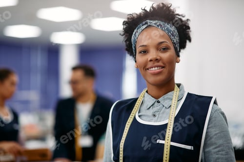 Preview: Portrait of happy black seamstress in clothing factory looking at camera.