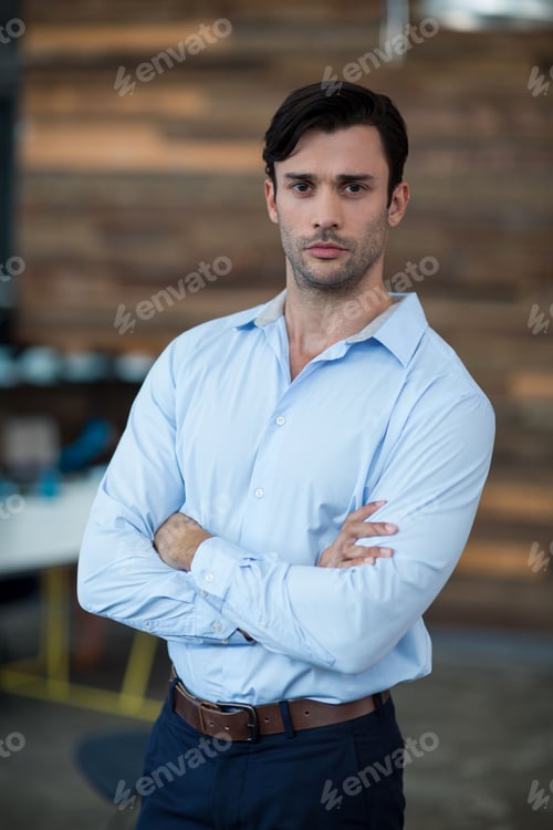 Preview: Standing male professional crossing arms in modern office interior, with wooden accent wall