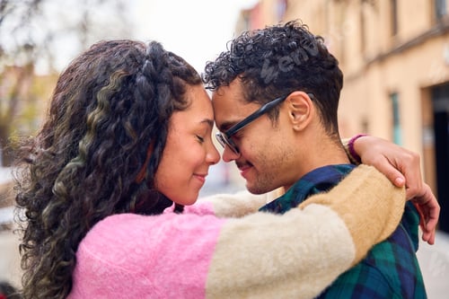 Preview: Young couple embracing and showing affection on city street
