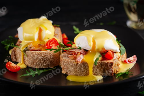 Preview: Sandwich with ham, poached egg, onion and arugula in a plate on a dark background