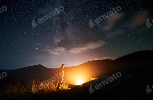 Preview: Man iswalking in mountains and lighting bonfire.