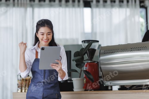 Preview: Woman celebrating business success with digital tablet in cafe