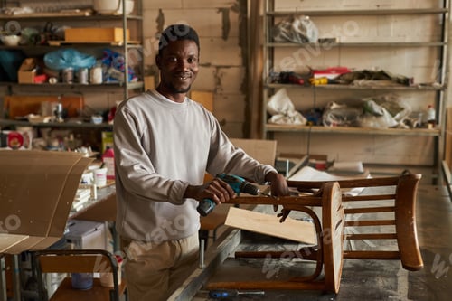 Preview: Smiling African American man restoring old furniture in workshop