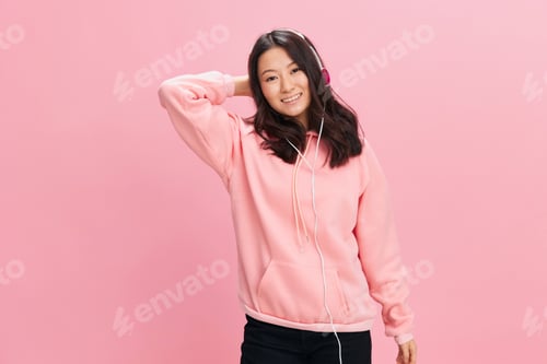 Preview: Enjoying Asian student young lady in pink hoodie sweatshirt with cute headphones smile touch head