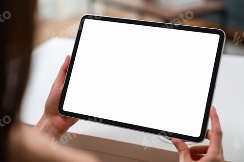 Preview: Woman hand holding digital tablet and sitting on the table in the house.