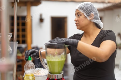 Preview: Latin cook adding oil to blender with green sauce
