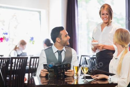 Preview: Smiling Business People Ordering Dinner From Pretty Waitress
