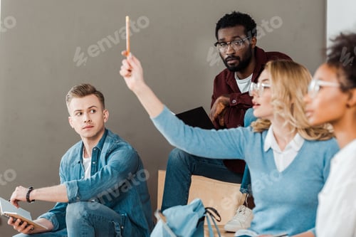 Preview: multicultural students in glasses with notebooks in lecture hall
