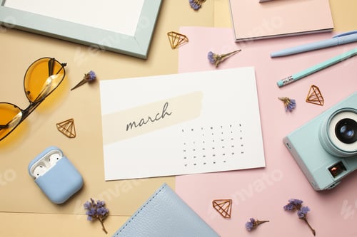 Preview: Flat Lay of March Calendar with Sunglasses, Earbuds, and Spring Flowers on Beige Background