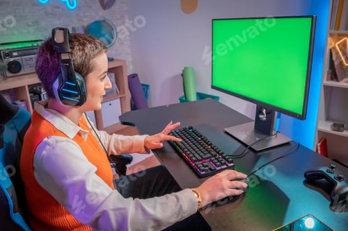 Preview: Pro gamer streaming video games with green screen mockup display in gaming neon lights home studio