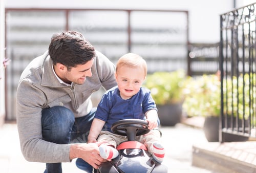 Preview: Father and and young son playing together, son riding toy car