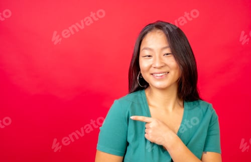 Preview: Happy chinese woman pointing aside in a blank space