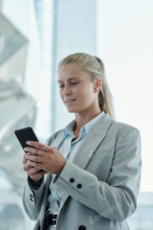 Preview: Portrait of young blond business lady holding smartphone in front of herself