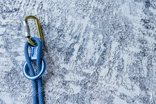 Preview: Isolated photo of climbing equipment. Part of carabiner lying on the white and grey colored surface