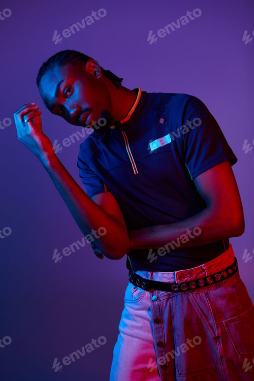 Preview: A young African American man showcasing stylish attire in a vibrant neon-lit studio