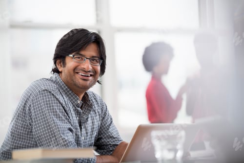Preview: A business environment, a young man seated at a desk using a laptop.