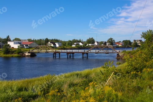 Preview: Scenic view of a blue river with lush vegetation and houses in Port Elgin, New Brunswick