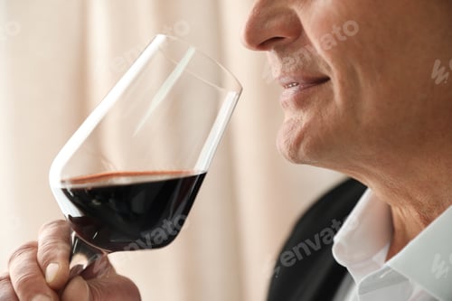 Preview: Senior man with glass of wine indoors, closeup