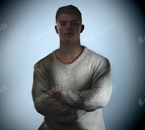 Preview: Young man wearing a loose sweater standing in the shadows and looking at the camera