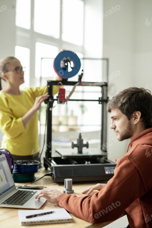 Preview: Serious designer concentrating on online work in front of laptop in office