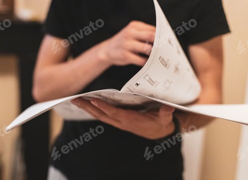Preview: A young man holds an instruction paper in his hands.
