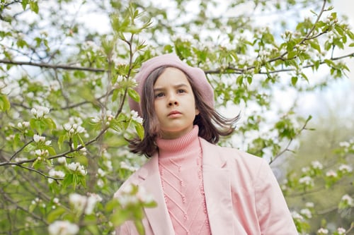 Preview: Portrait of little girl stands in a blooming white apple tree in the park.