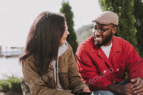 Preview: Positive Young International Couple Having A Pleasant Talk While Resting Outdoors