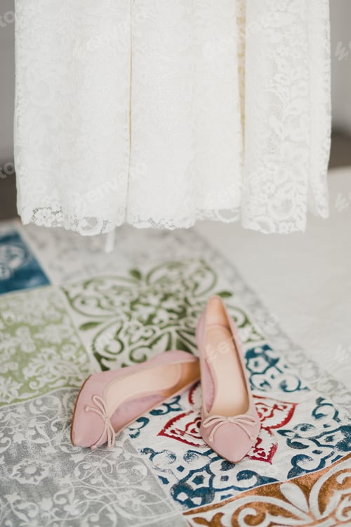 Preview: Bridal morning details composition. Pink shoes and wedding dress in the bedroom.