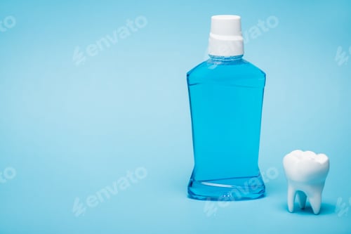 Preview: White model of tooth and bottle of mouthwash on blue background with copy space