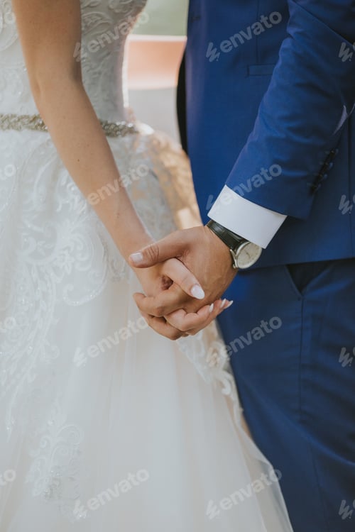 Preview: Vertical shot of the groom and the bride holding hands at the wedding ceremony