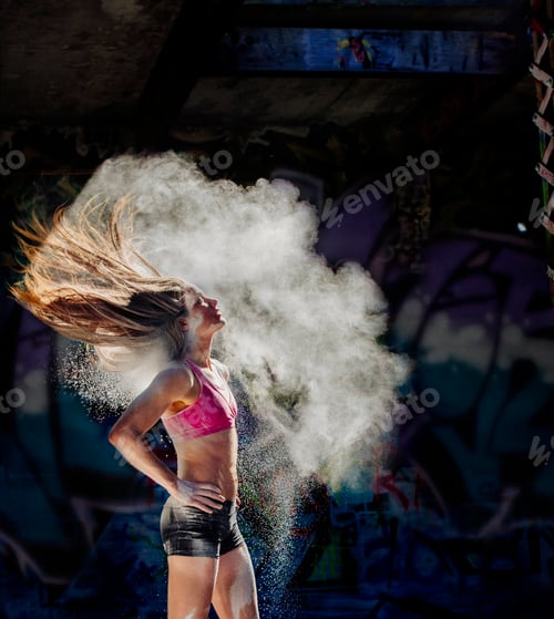 Preview: Woman standing with hands on hips throwing powder covered hair back