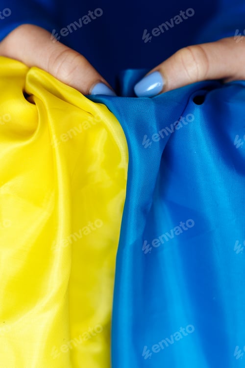 Preview: Woman with nails painted at the blue and yellow colours holding yellow-blue flag of Ukraine
