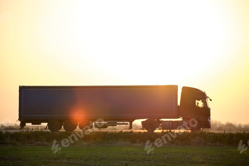 Preview: Semi-truck with cargo trailer driving on highway hauling goods in evening. Delivery transportation