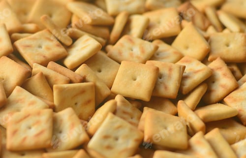 Preview: A lot of small cookies are square shaped. A pattern of a yellow salt cracker