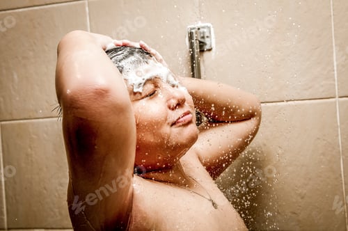 Visualização: Retrato de um jovem feliz no chuveiro lavando o cabelo.