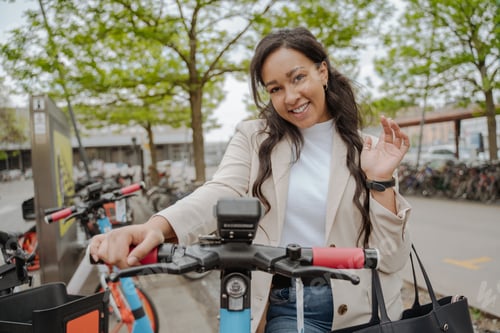 Preview: Smiling woman salutation, riding on electric scooter on the street