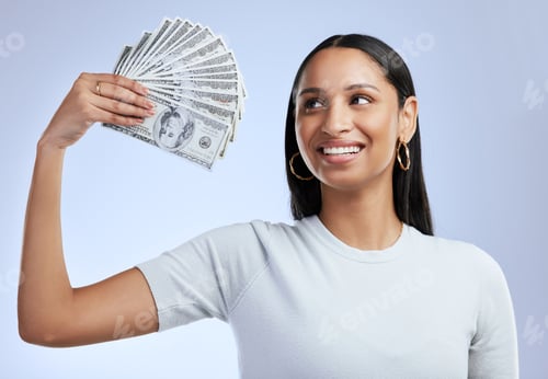 Preview: Shot of a young woman holding up bank notes against a grey background