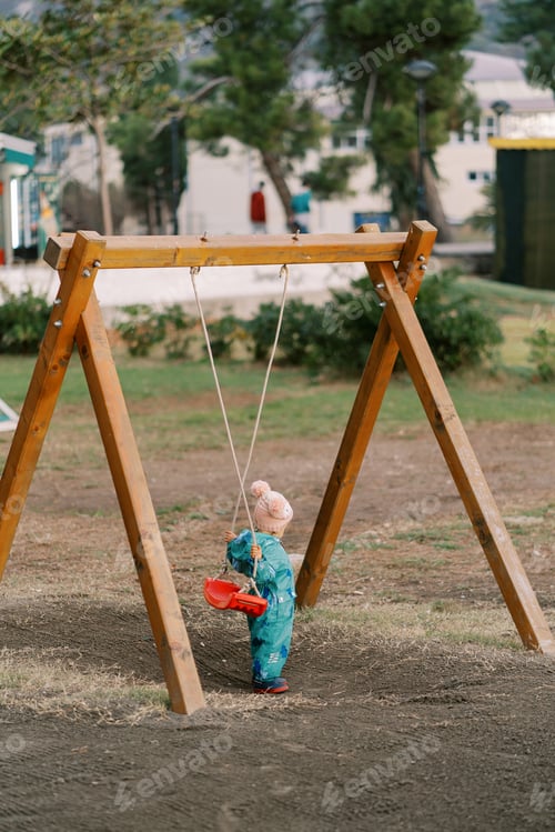 Preview: Little girl holds the swing seat behind her to sit on. Back view