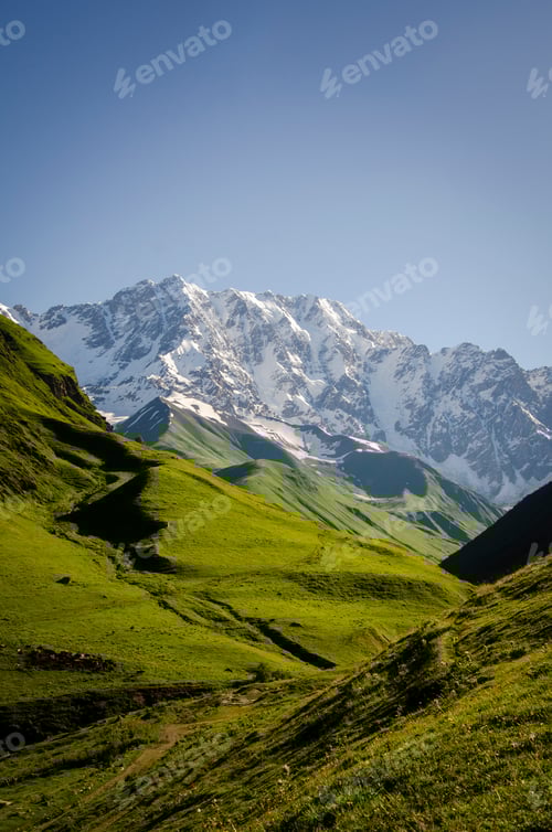 Preview: Green Valley and Snowy Mountain Peaks on Sunny Day