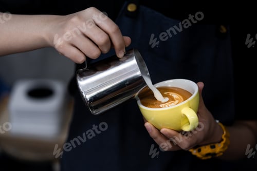Preview: barista hand holding and pouring hot milk for prepare latte art