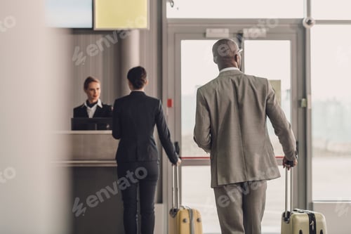 Preview: rear view of businesspeople walking to airport check in counter