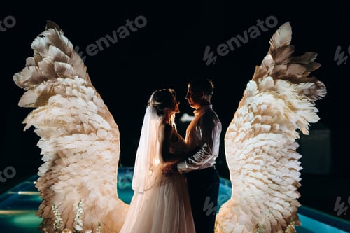 Preview: cutting the wedding cake against the backdrop of white wings