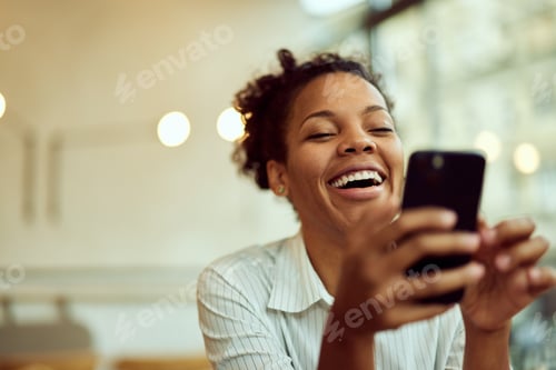 Preview: Curly-haired African female, using a mobile phone, watching something online, and laughing.